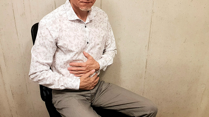 Magenkrebs-Symptome erkennen: Mann hält sich Bauch – Sinnbild für frühe Anzeichen, Ursachen, Diagnose und Untersuchungsmethoden.