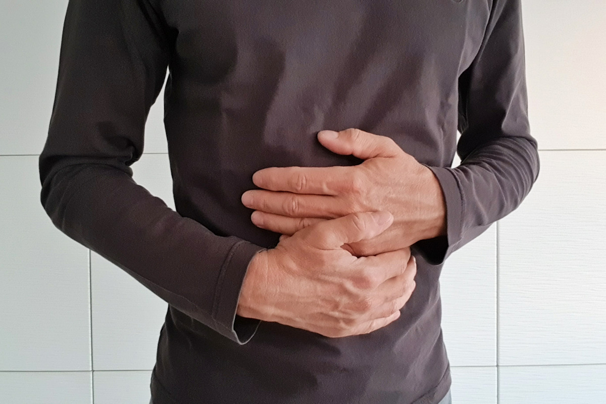 Patient mit fortgeschrittenen Symptomen von Magenkrebs hält sich mit beiden Händen den Bauch
